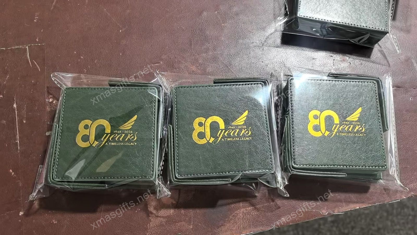 Three green leatherette coasters with gold foil logo